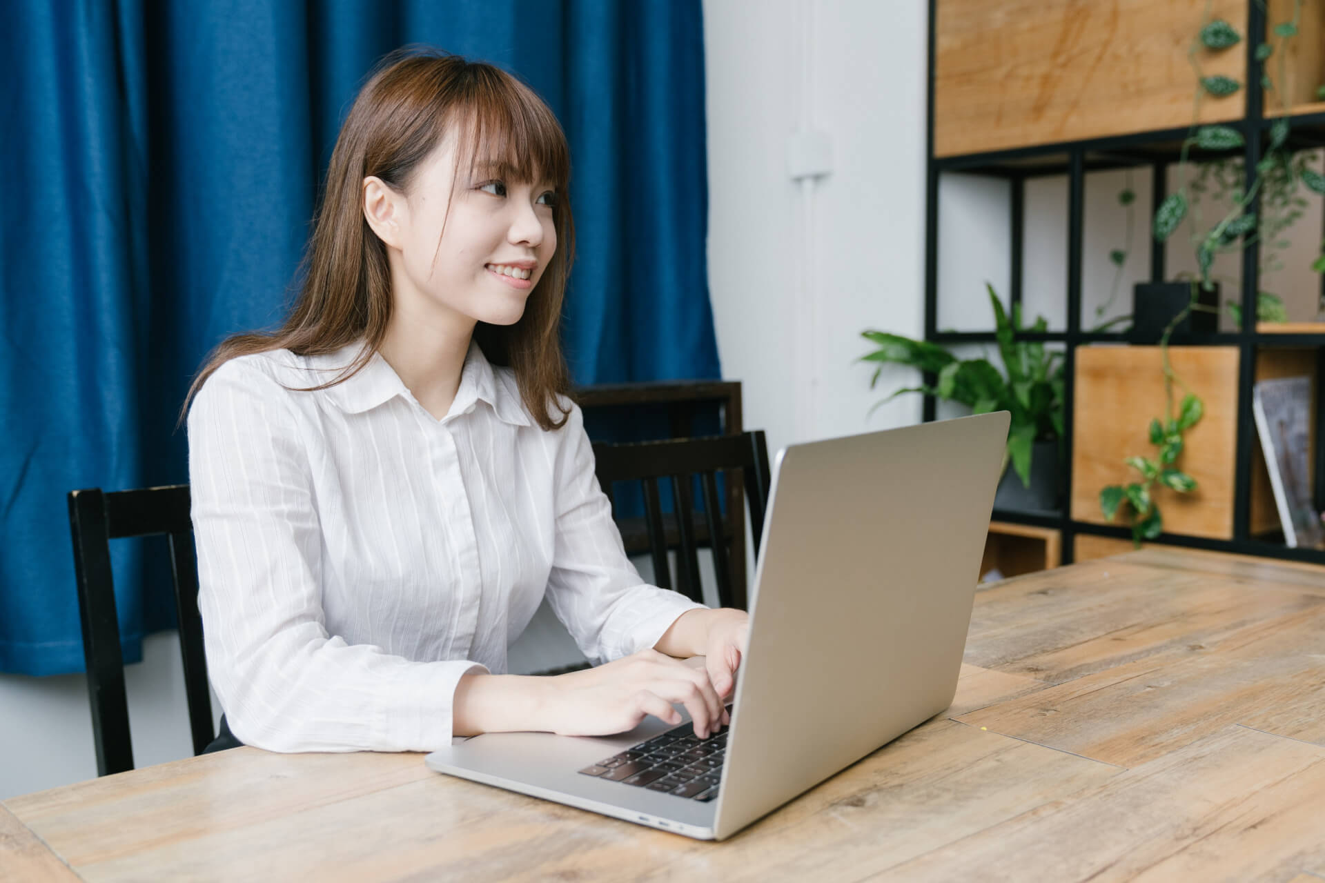 オフィスで笑顔の女性がノートパソコンを操作