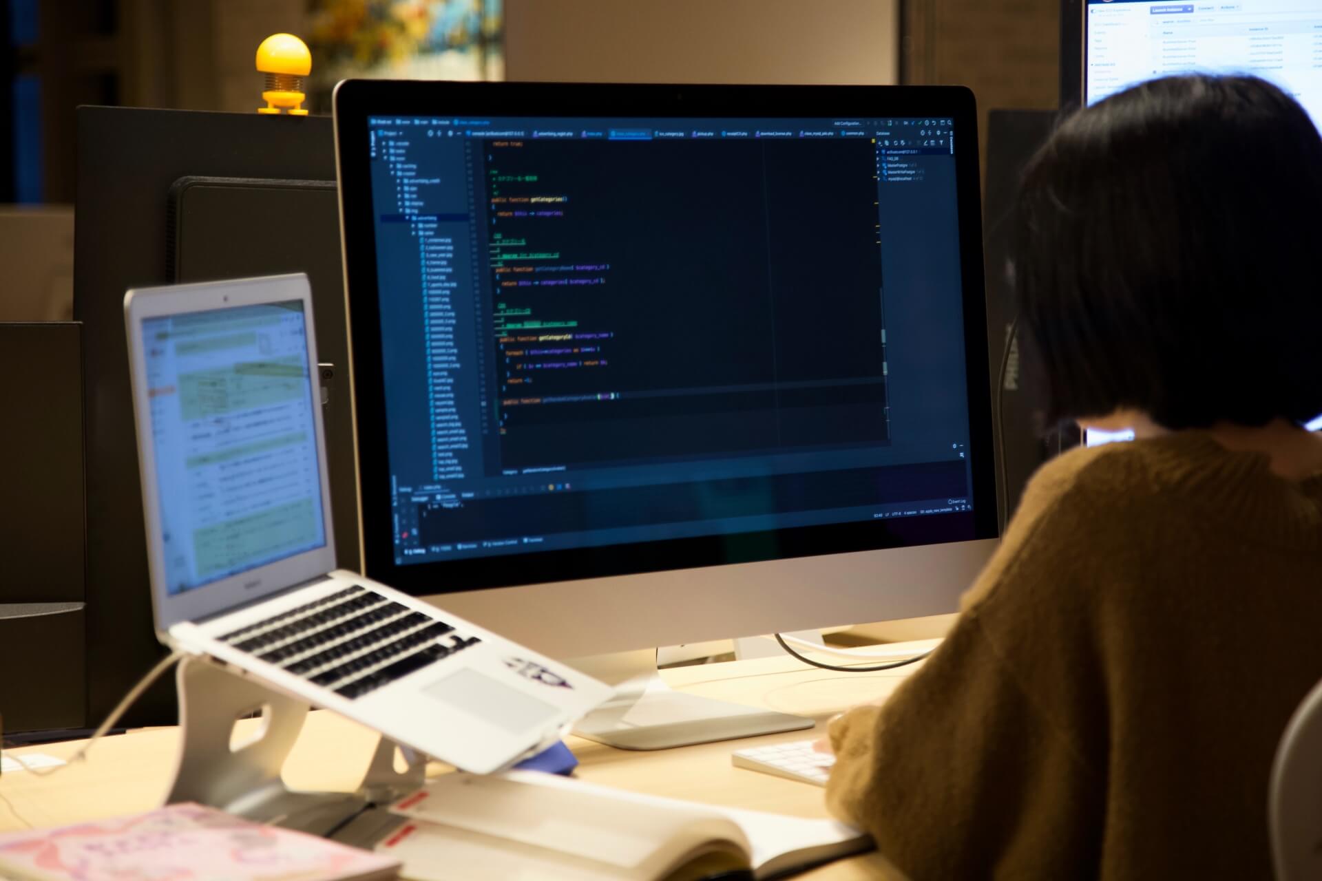 デュアルモニターでコーディングする女性